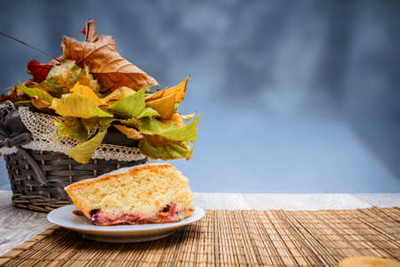 A piece of sponge cake bread on a straw bedding on a background of autumn leaves of a small...