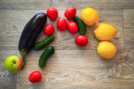 A variety of vegetables laid out the colors of a wooden tabletop before cooking.Tomatoes, cucumbers and eggplants, along with lemons and grapes, are spread out on a light wooden tabletop before cooking.の写真素材