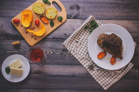A piece of meat, sprinkled with spices, baked with baked carrot slices on a white plate, fork, linen...