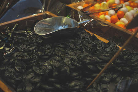 a wooden box filled to the top with black licorice candy and an iron spoon
Pastry shop with wooden boxes filled to the top filled with sweets.
の写真素材