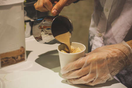 A man prepares cocoa spilling hot drink in cups of air with white marshmallows.の写真素材