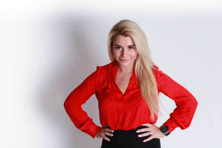 The girl on the white-gray gradient background. The girl in the red blouse hands on hips looking...