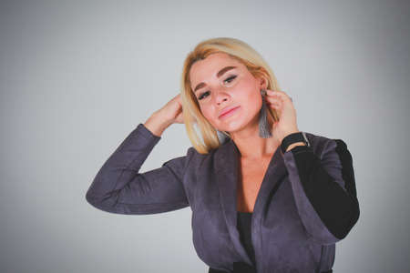 White Light gray gradient background. A girl in a gray office suit looks into the camera straightens...
