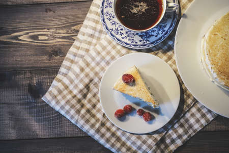 Top view of a dark tabletop with a white checkered linen napkin on which is a white and blue...