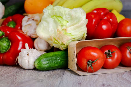 Against the background of a light countertop, tomatoes, cucumber, red pepper, garlic, iceberg salad. Still life, composition of fresh vegetables.の写真素材