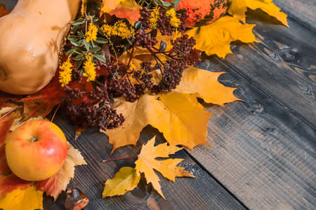 On a gray wooden tabletop on autumn yellow leaves, autumn burgundy and yellow small flowers, yellow...