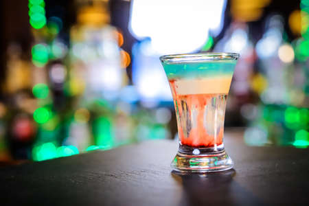 In the glass, the cocktail is brown-red, the top is white and the top is emerald, which is set on...