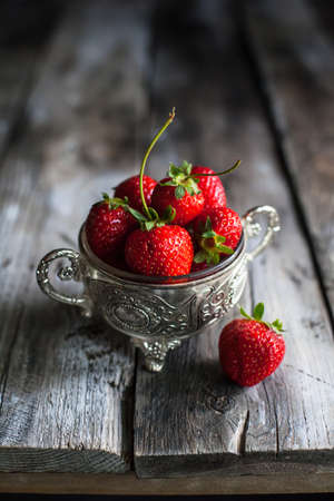 Strawberries in a cup on a wooden backgroundの写真素材