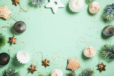 Christmas composition. Gingerbread, pine branches, white and green decorations on green background....