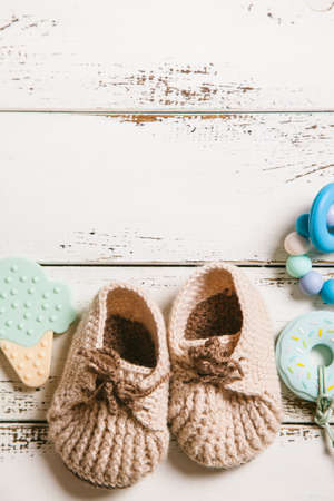 Newborn baby bootees and teethers on white wooden background with copy space. Baby fashion concept. Top view, flat lay.の写真素材