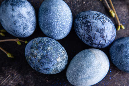 Happy easter concept. Multicolored easter painted eggs in blue tones and branches with buds on a...