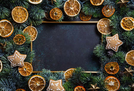 Christmas composition. Frame with gingerbread, pine branches and dried orange chips slices on green background. Christmas, winter, new year concept. Flat lay, top view, copy space.の写真素材