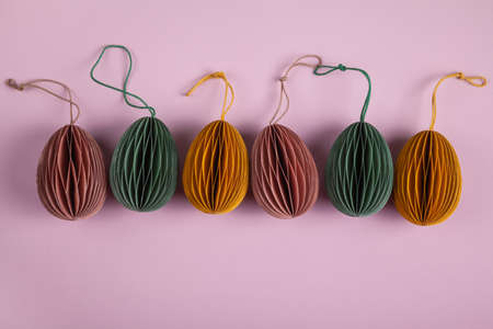 Happy easter concept. Multicolored easter eggs made of paper on a pastel pink background. Flat lay,...