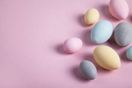 Happy easter concept. Multicolored easter painted eggs on a pastel pink background. Flat lay, top view, copy space.の写真素材