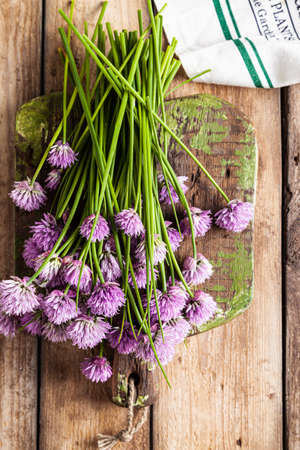Schnitt-onion, chives flowers on a wooden board on a wooden background.の写真素材