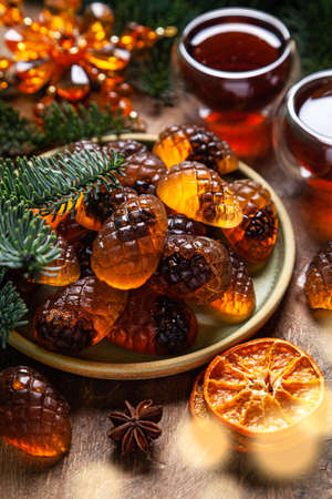 Marmalade pine cones in a ceramic plate and pine branches on a wooden background. A Christmas card.の写真素材