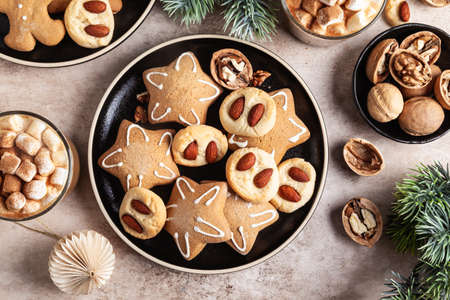 Gingerbread stars and cookies with almonds in a black ceramic plate on a beige background. Christmas concept.の写真素材