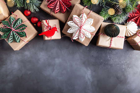 Christmas gift boxes decorated with red, green, white snowflakes made of paper on a gray background.