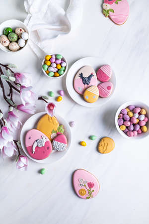 Handmade Easter gingerbread cookies, chocolate eggs in a white plates and branches of blooming...