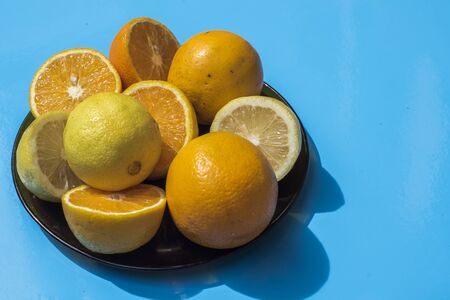 plate with oranges and lemons on a light blue backgroundの写真素材
