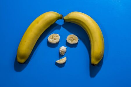 smiley face made with bananas on light blue backgroundの写真素材
