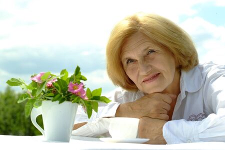 Beautiful Caucasian elderly woman sitting with a flowerの写真素材