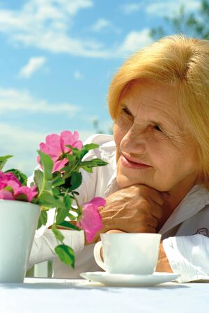 Beautiful Caucasian elderly woman sitting with a flowerの写真素材