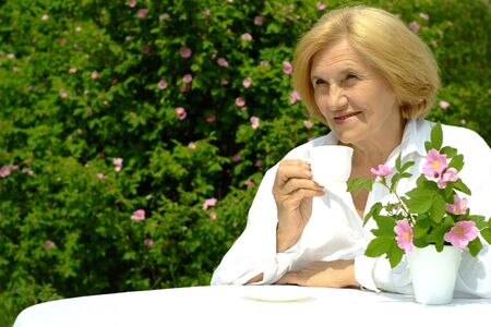 Beautiful Caucasian elderly woman sitting with a flowerの写真素材