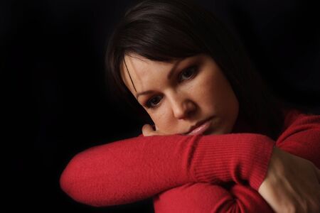 Happy sad Caucasian female sitting on a dark background