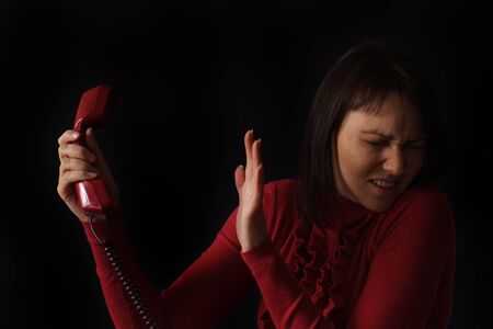 sad Caucasian woman talking on the phone on a dark backgroundの写真素材