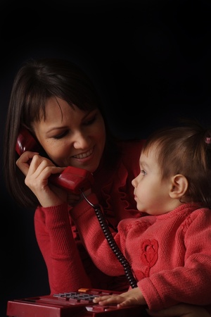 Happy Caucasian happy mother and daughter talk on the phone on a dark backgroundの写真素材