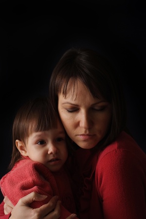 A pretty Caucasian mother with a sad crying daughter on a dark backgroundの写真素材