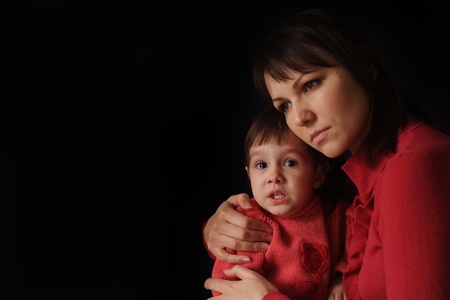 A pretty Caucasian mama with a sad crying daughter on a dark backgroundの写真素材