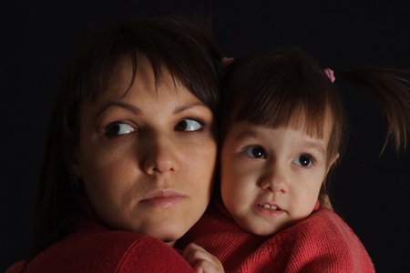 Nice sad Caucasian woman with a daughter on a dark backgroundの写真素材