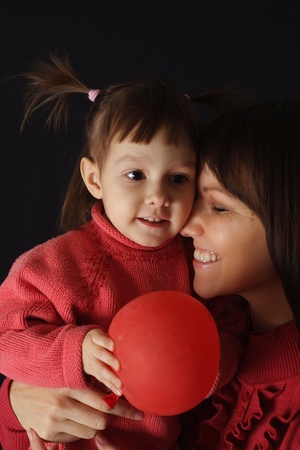 Pretty Caucasian happy mom with a daughter and an air ball on a dark backgroundの写真素材