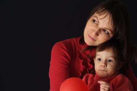 Beautiful happy mom with a daughter and an air ball on a dark backgroundの写真素材