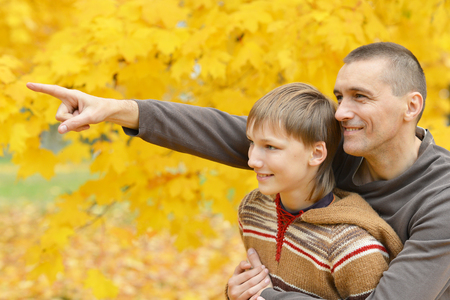 Father and son on a walk during the fall of the leaves in the parkの写真素材