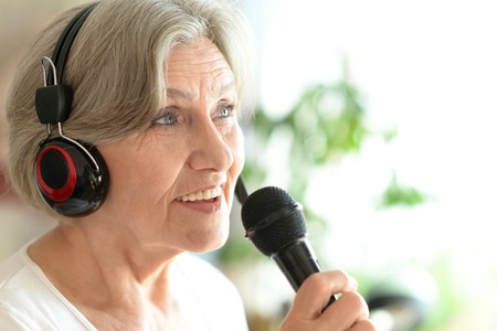 Senior woman singing into microphoneの写真素材