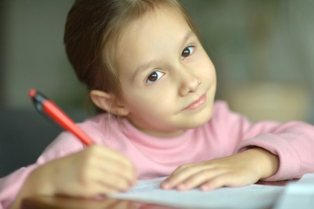 portrait of a little girl writing at tableの写真素材