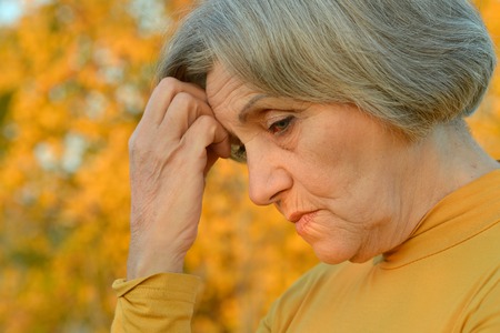 Nice sad old woman on the autumn backgroundの写真素材
