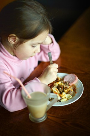 Little Caucasian baby eats at the tableの写真素材