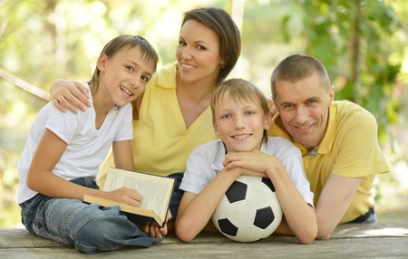 Portrait of happy family at wooden table with football ball and book