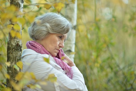 Nice sad old woman on the autumn backgroundの写真素材