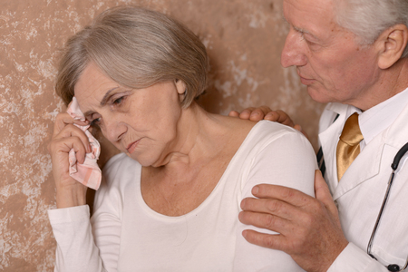 Close-up portrait of a sad elder couple on brown backgroundの写真素材