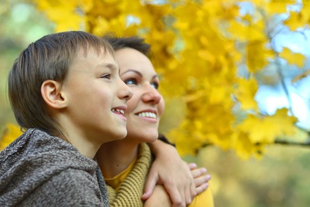 Beautiful mother with a boy on a walk during the fall of the leaves in the parkの写真素材