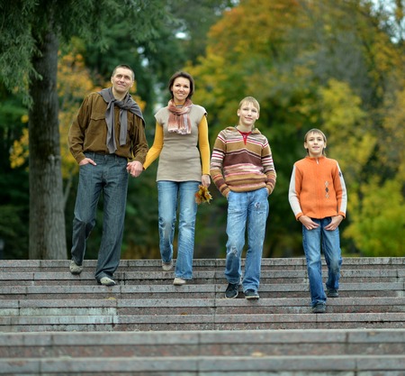 Happy family of four standing together in the park in autumn