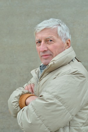 Thoughtful senior man at grey outdoor backgroundの写真素材