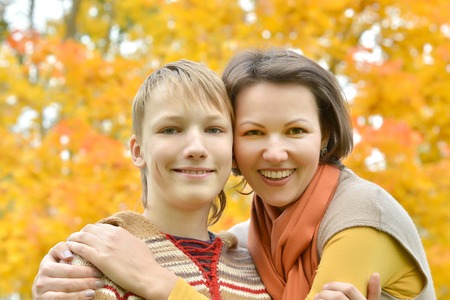 Beautiful mother with a boy on a walk during the fall of the leaves in the parkの写真素材