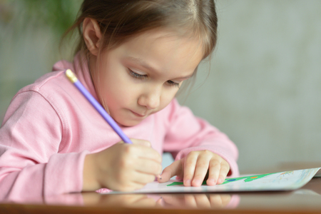 Portrait of a little girl drawing at tableの写真素材