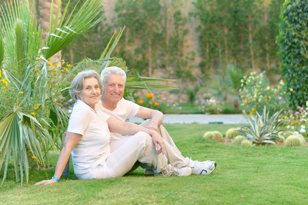 Senior couple sitting on grass at hotel resortの写真素材